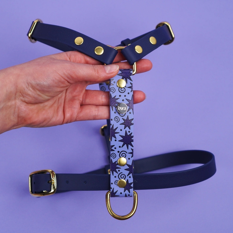 Detal szelek z Biothane: mosiężne okucia i taśma z nadrukiem Gwiazdki na fioletowym tle.