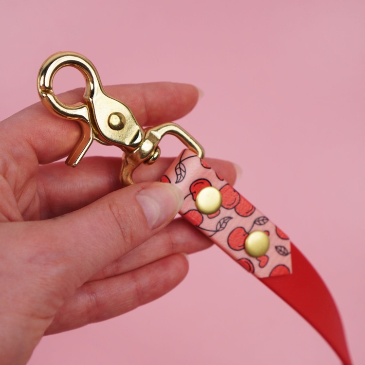 Zbliżenie karabińczyka: smycz miejska z Biothane dla psa, solidne okucia i mocowanie, wzór Wiśnie i serduszka.