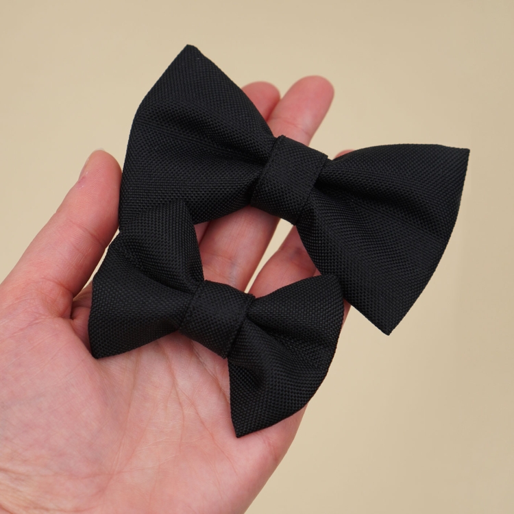 czarna kokardka dla psa w dwóch rozmiarach S i M trzymana w dłoni