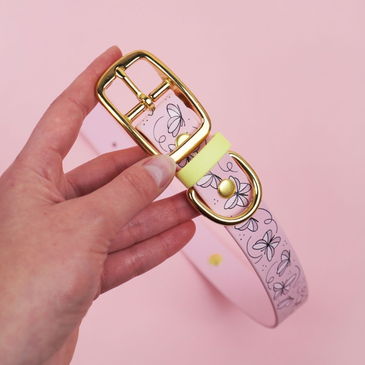 Detal obroży dla psa we wzorze Motyle z widoczną złotą sprzączką.