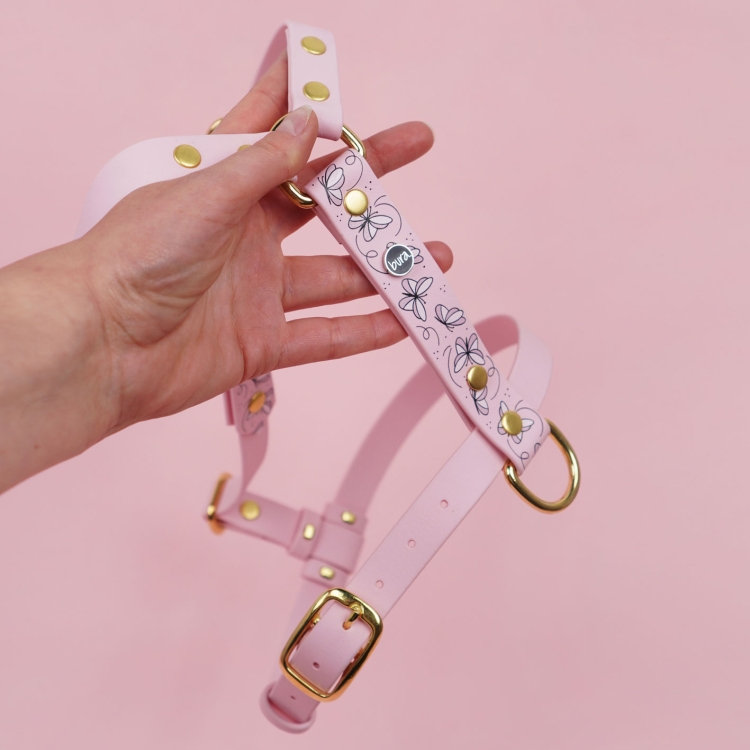 Szelki dla psa we wzorze Motyle pokazane w ułożeniu na różowym tle.