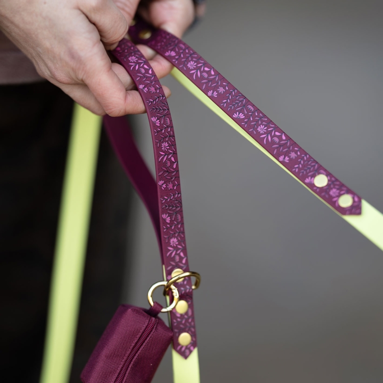 Detal smyczy miejskiej dla psa we wzorze Łąka trzymanej w dłoni.