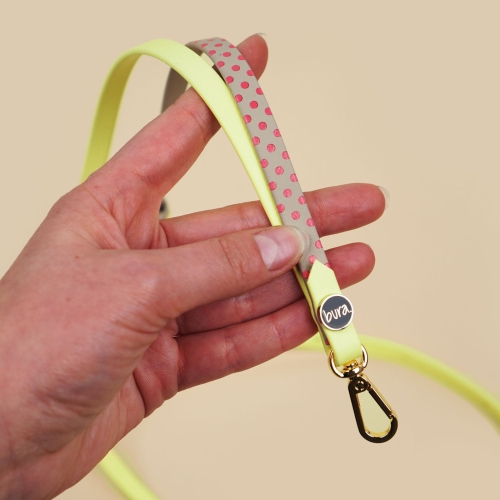 Personalizowana smycz na telefon w kropki z Biothane, hands-free, z regulacją i złotym karabińczykiem – zbliżenie produktu w dłoni